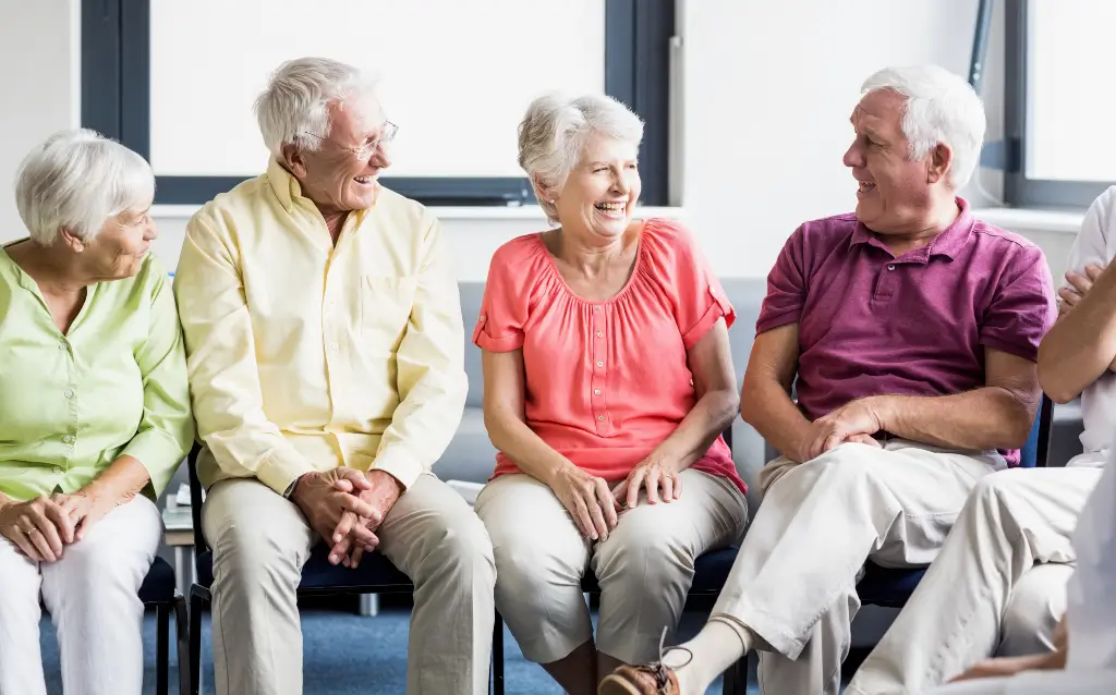 Joyful group of seniors smiling and socializing together during a community gathering at a senior living community.